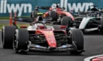 Red Formula 1 race car leads the pack on a track with several cars close behind
