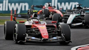 Red Formula 1 race car leads the pack on a track with several cars close behind