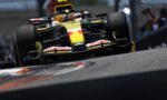 Low-angle shot of a yellow Renault Formula 1 car speeding through a corner, front wing and tire wear visible.