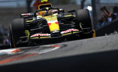 Low-angle shot of a yellow Renault Formula 1 car speeding through a corner, front wing and tire wear visible.