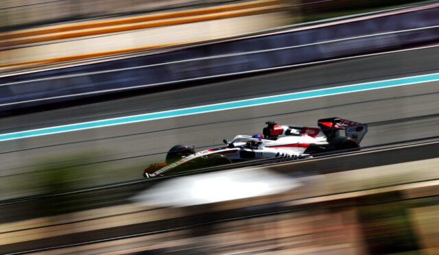 Formula 1 car speeding along a race track with blurred colorful barriers in the background.