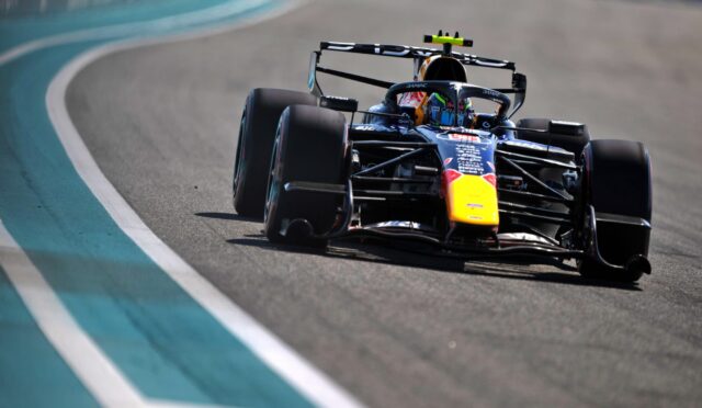 Formula 1 race car speeding around a curve on a race track, with teal run-off area on the left side