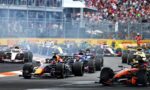 Multiple Formula 1 cars race off at the start on a city track with a large crowd in the stands behind a safety fence.