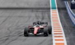 Red Ferrari Formula 1 car on track, close to orange-and-white striped runoff on the right.