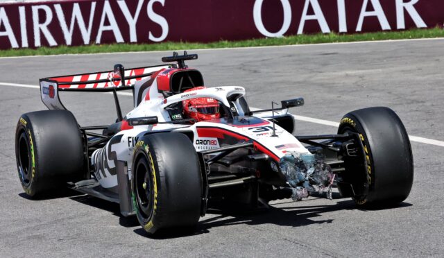 Open-wheel race car on a racetrack with a damaged nose and debris under the front, Qatar banner in the background.