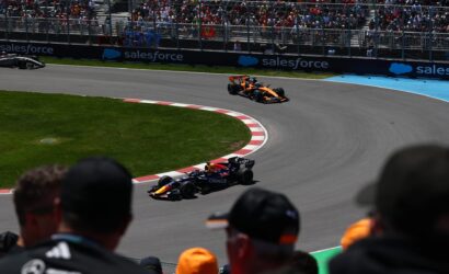 Orange Formula 1 car on a curved track with cheering spectators behind fencing and Salesforce banners?