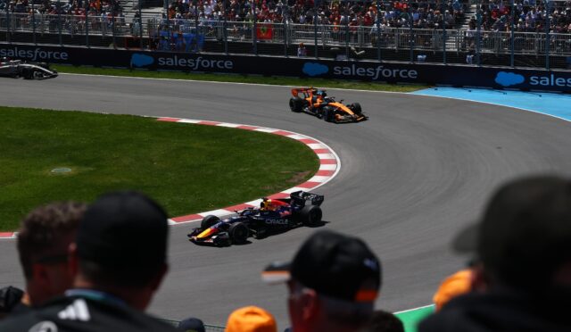 Orange Formula 1 car on a curved track with cheering spectators behind fencing and Salesforce banners?