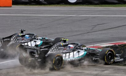 Mercedes Formula 1 cars from the Petronas team racing on a track, smoke and dust rising from the tires with sponsor logos visible