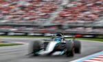 Blurred Formula 1 car racing on a track with a packed stadium in the background.