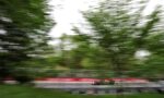 Green go-kart racing on a track with blurred trees in the background, conveying high speed.