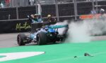 Blue Formula 1 car drifting with smoke near the pit wall, crew signaling in the background on a race track in Montreal.",