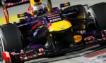 Close-up of a purple Red Bull Renault Formula 1 car with a driver in helmet, on a race track close to the camera.