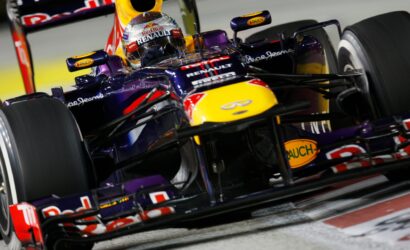 Close-up of a purple Red Bull Renault Formula 1 car with a driver in helmet, on a race track close to the camera.