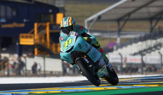 Moto racer leaning into a turn on a turquoise-blue race bike with number 97 and Leopard branding on a sunny track.