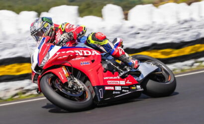Motorcycle racer on a red Honda sportbike leaning into a turn on a race track