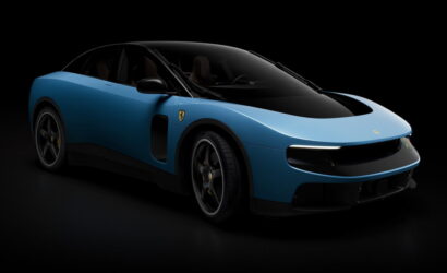 Blue Ferrari sports car in a dark studio, front three-quarter view highlighting its sleek curves and emblem on the fender.