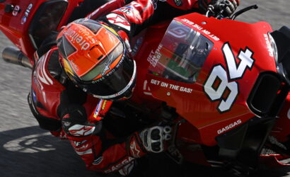 Motorcycle racer in red gear leaning into a turn on a red race bike numbered 54.