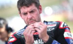 Motorcycle racer in Yamaha gear concentrates while handling a small object in his hands before a race.