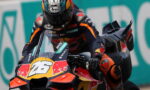 MotoGP rider leaning into a turn on a numbered race bike (26) with Red Bull livery and sponsor decals.