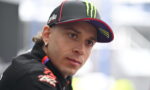 Close-up of a man wearing a black cap with neon green Monster logo, looking to the side.