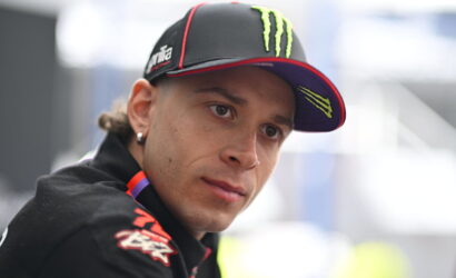 Close-up of a man wearing a black cap with neon green Monster logo, looking to the side.
