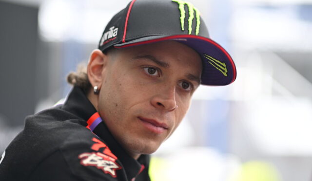 Close-up of a man wearing a black cap with neon green Monster logo, looking to the side.