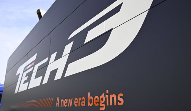 Close-up of a dark wall with a large white 'TECH' logo and the orange slogan 'A new era begins' beneath it.