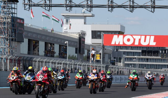 Motorcycle racers sprinting off the starting line on a straight track with a large Motul banner in the background