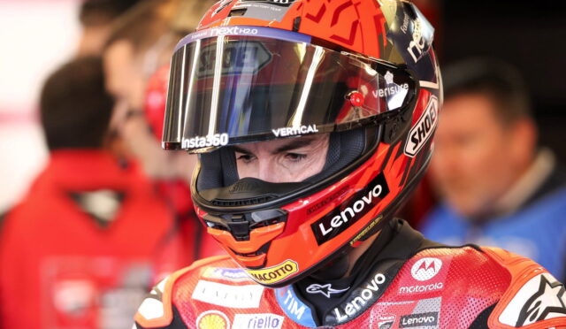 MotoGP rider wearing a red helmet with Lenovo and Motorola logos, close-up portrait in the pit area.