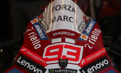 Red racing motorcycle front with number 99 and sponsor logos (Lenovo, Monster Energy, Shell, Frecciarossa) and 'FORZA MARC' on a white windshield.