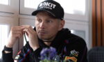 Man wearing a black cap labeled 'ROKiT Oxygen' adjusts a strap while seated indoors.