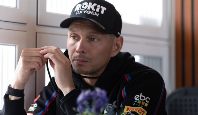 Man wearing a black cap labeled 'ROKiT Oxygen' adjusts a strap while seated indoors.