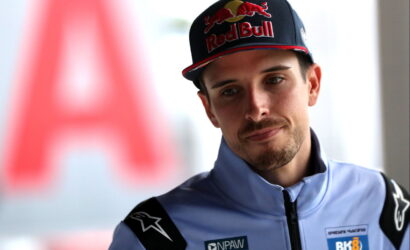 Portrait of a young man in a light-blue racing suit and a Red Bull cap, looking to the left.