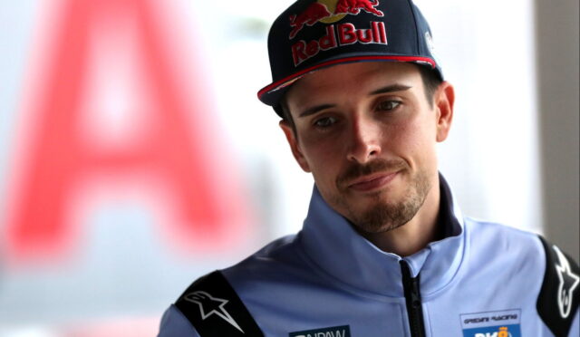 Portrait of a young man in a light-blue racing suit and a Red Bull cap, looking to the left.