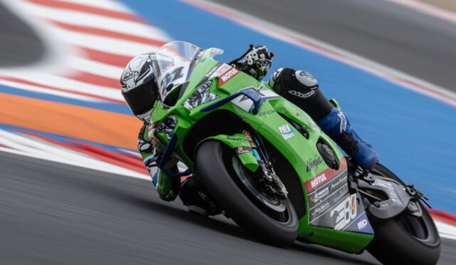 Green racing motorcycle with rider leaning into a turn on a racetrack, Motul sponsor logos visible.