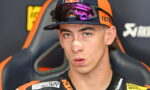 Portrait of a young motocross racer wearing a Red Bull cap and reflective goggles, with a bandage on his nose and a focused expression.