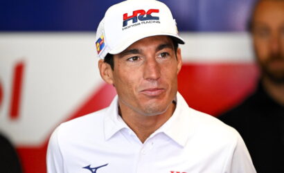 Man in a white polo shirt and a Honda Racing cap at a media event.