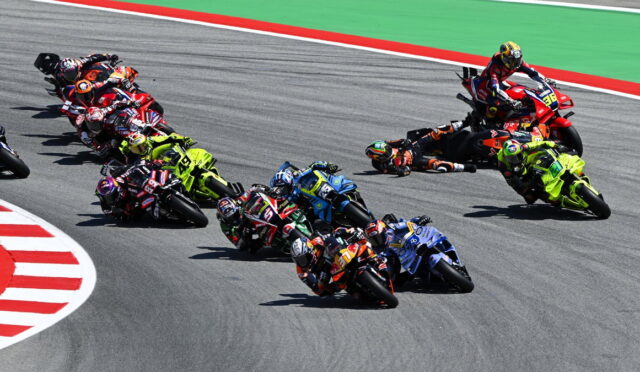 Group of motorcycle racers leaning into a sharp turn on a track, colorful racing bikes closely bunched together.