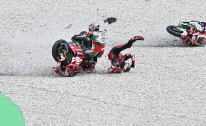 Racing motorcyclist crashes on gravel track as another rider slides nearby in a red suit and bike nearby