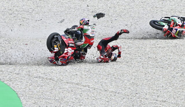 Racing motorcyclist crashes on gravel track as another rider slides nearby in a red suit and bike nearby