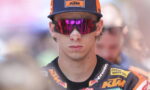 Moto rider wearing a Red Bull KTM cap and mirrored pink sunglasses, in a racing suit with sponsor logos.
