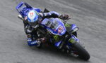 Motorcycle racer in blue Yamaha suit leaning into a turn on a race track, number 46 on the bike with Monster Energy branding.