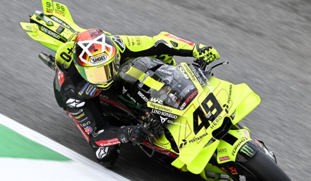 Motorcycle racer in bright yellow-green bike leaning at a track, number 46, mid-turn on a race circuit.