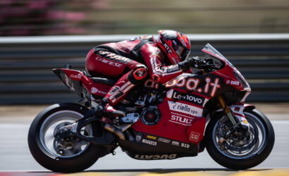 Rider in red racing suit on a red Ducati motorcycle speeding on a race track with sponsor logos visible