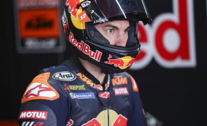 Close-up of a motorcycle racer wearing a Red Bull helmet and KTM racing suit, concentrating ahead