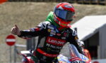 Motorcycle racer in a red Suomy helmet and Lenovo racing suit giving a thumbs-up on the track.