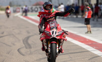 Rider on a red Aruba.it/Lenovo race bike raises a fist in celebration on the pit lane with blurred crew in the background
