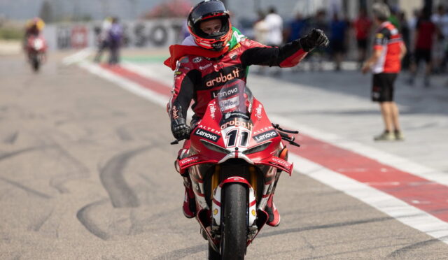 Rider on a red Aruba.it/Lenovo race bike raises a fist in celebration on the pit lane with blurred crew in the background