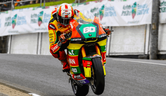 Rider in a bright, multicolor racing suit and helmet leaning into a corner on a race track with the number 60 on the bike.