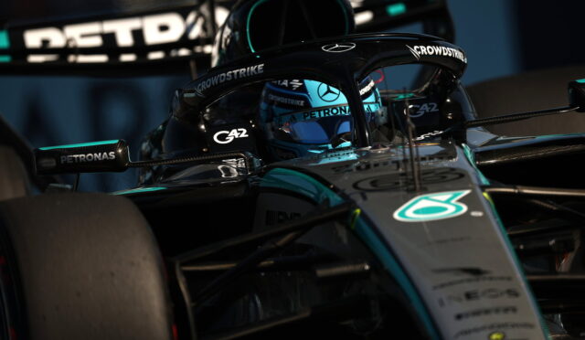 Mercedes-AMG Petronas Formula 1 car in teal and black, driver visible in the cockpit with blue helmet, close-up on front and halo protection.